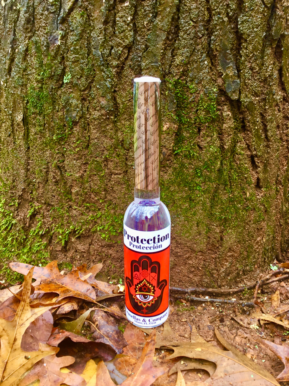 Bottle of spiritual cologne labeled 'Protection' against a tree trunk background