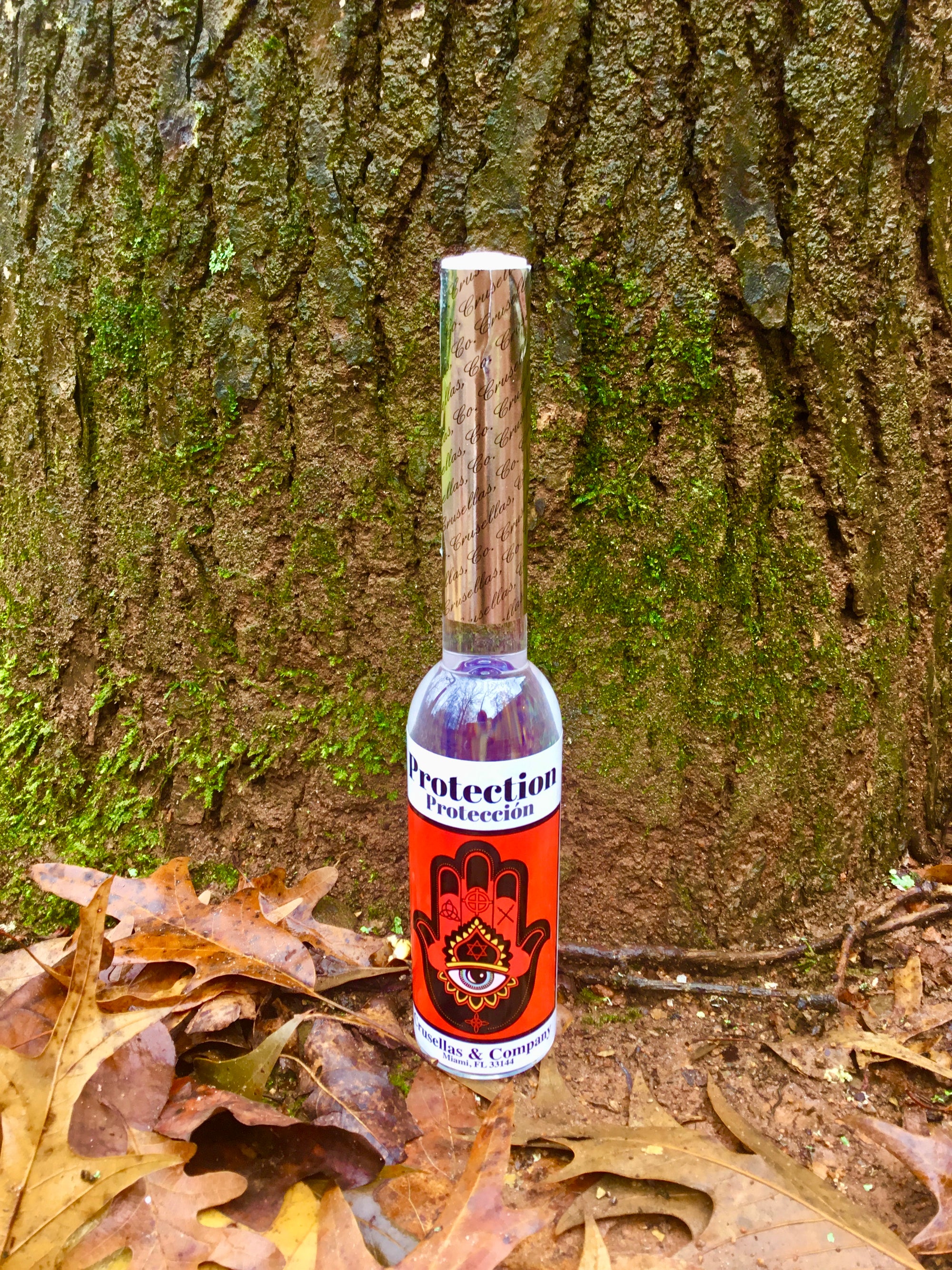 Bottle of spiritual cologne labeled 'Protection' against a tree trunk background